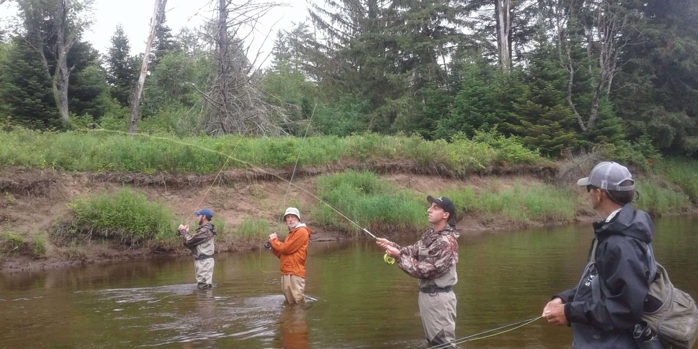 Four men fly fishing in river