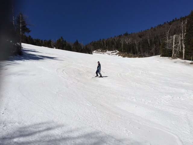 Single skier in blue jacket coming down the hill.