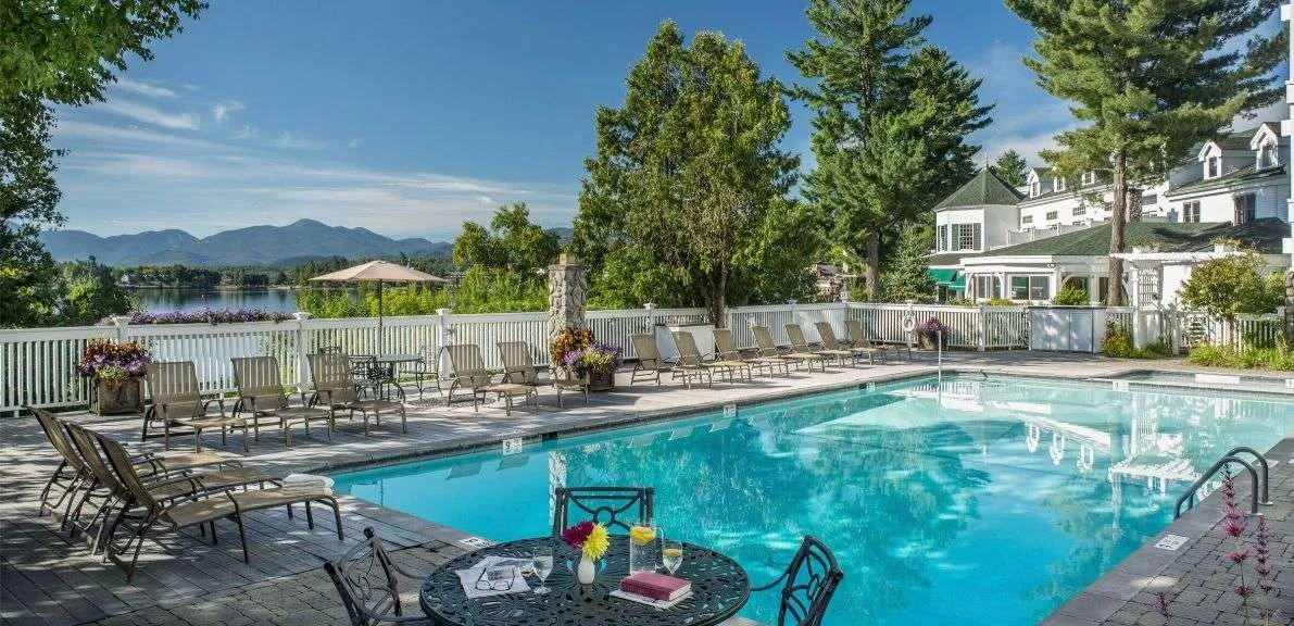 Mirror Lake Inn's outdoor swimming pool on a sunny day with a mountain view.