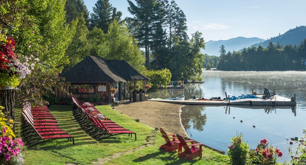 Mirror Lake Inn's private beach with lounge beach chairs, a cabin, and a dock.