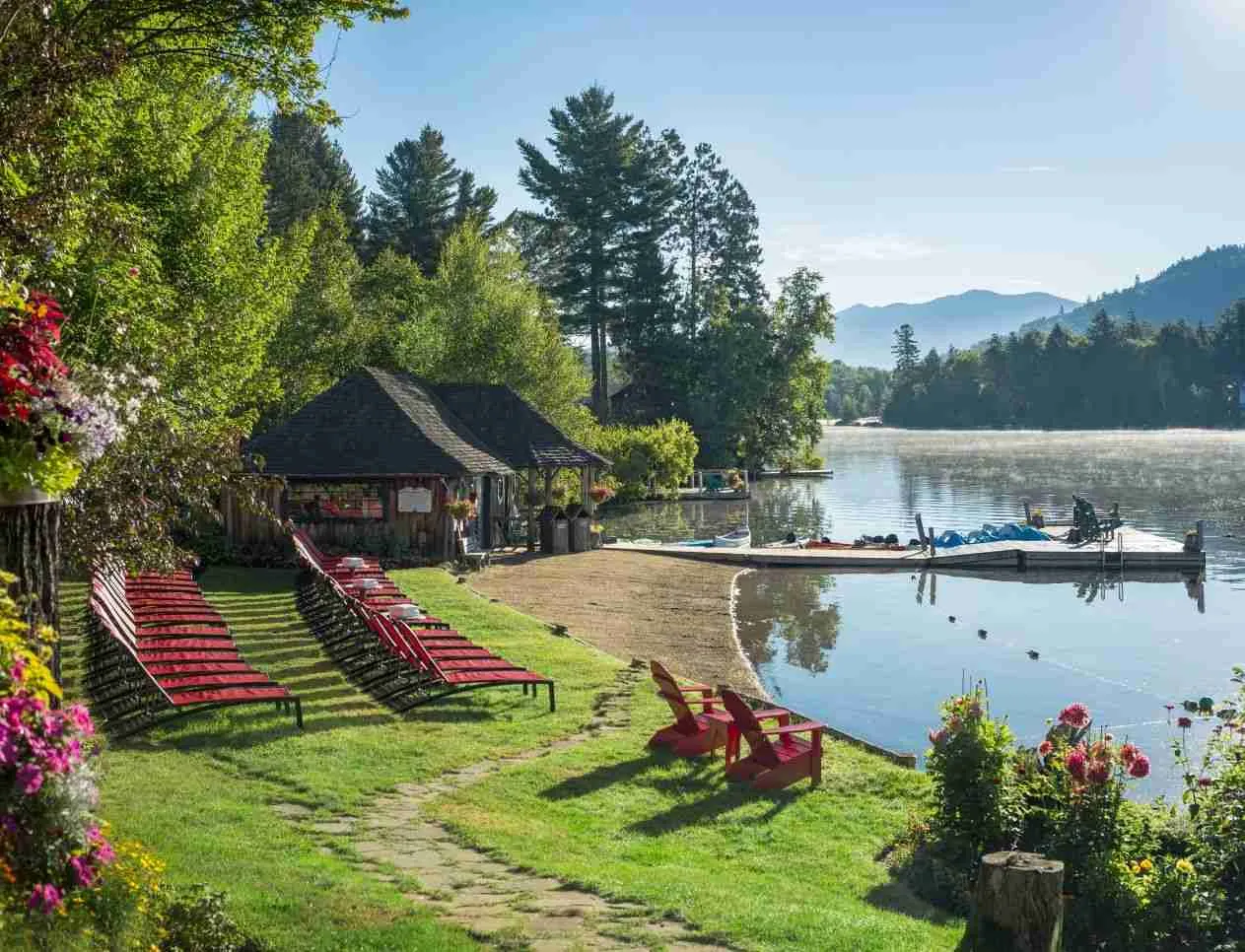 Mirror Lake Inn's private beach with lounge beach chairs, a cabin, and a dock.