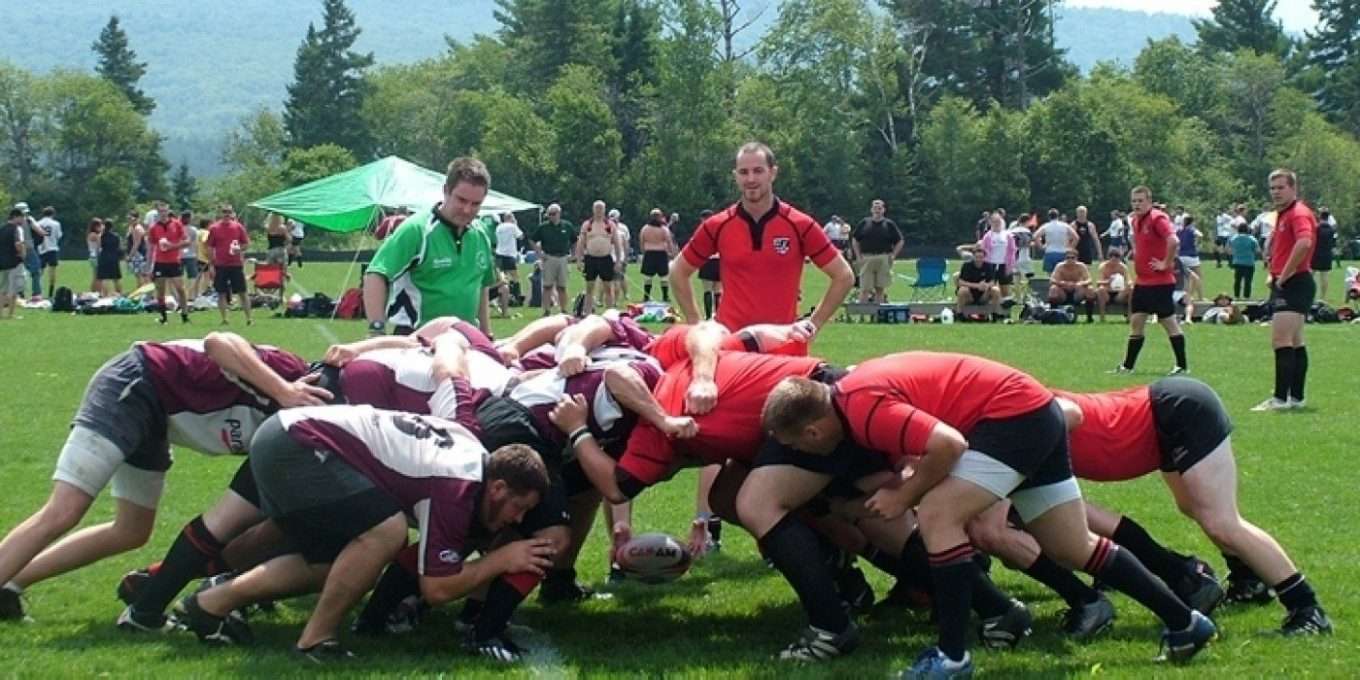 Players huddled in rugby scrum on a field.