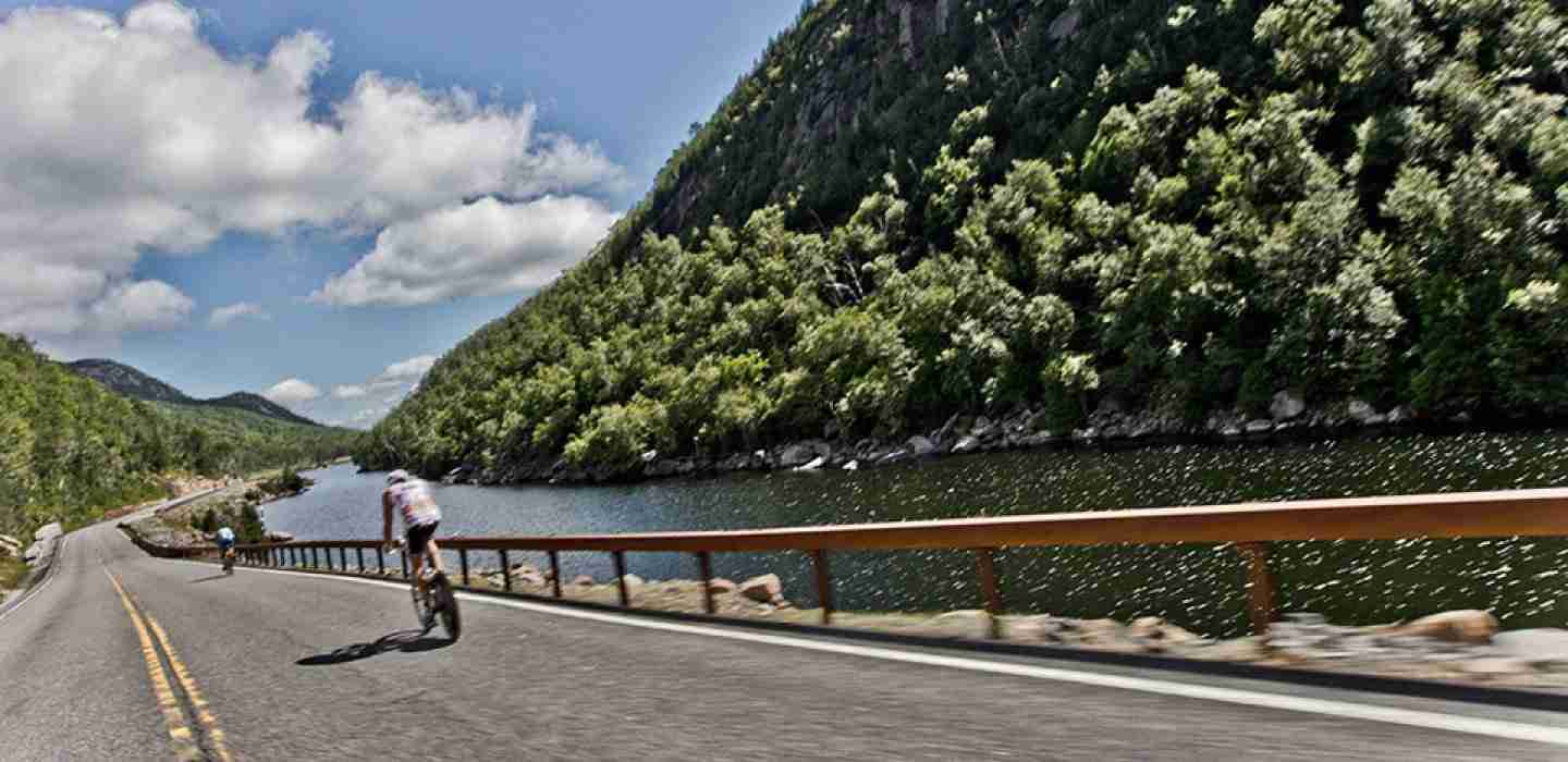 A road cyclist cycling a road in a valley alongside a river