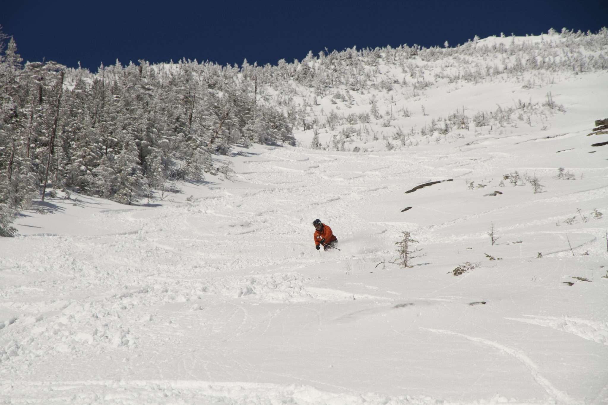 Skiier coming down mountain in deep powder