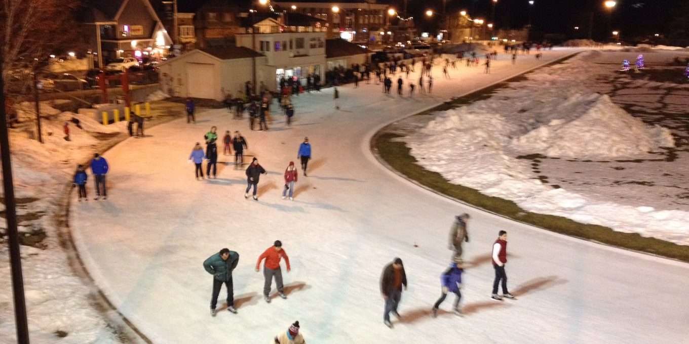 Numerous people skating at the oval at night time.