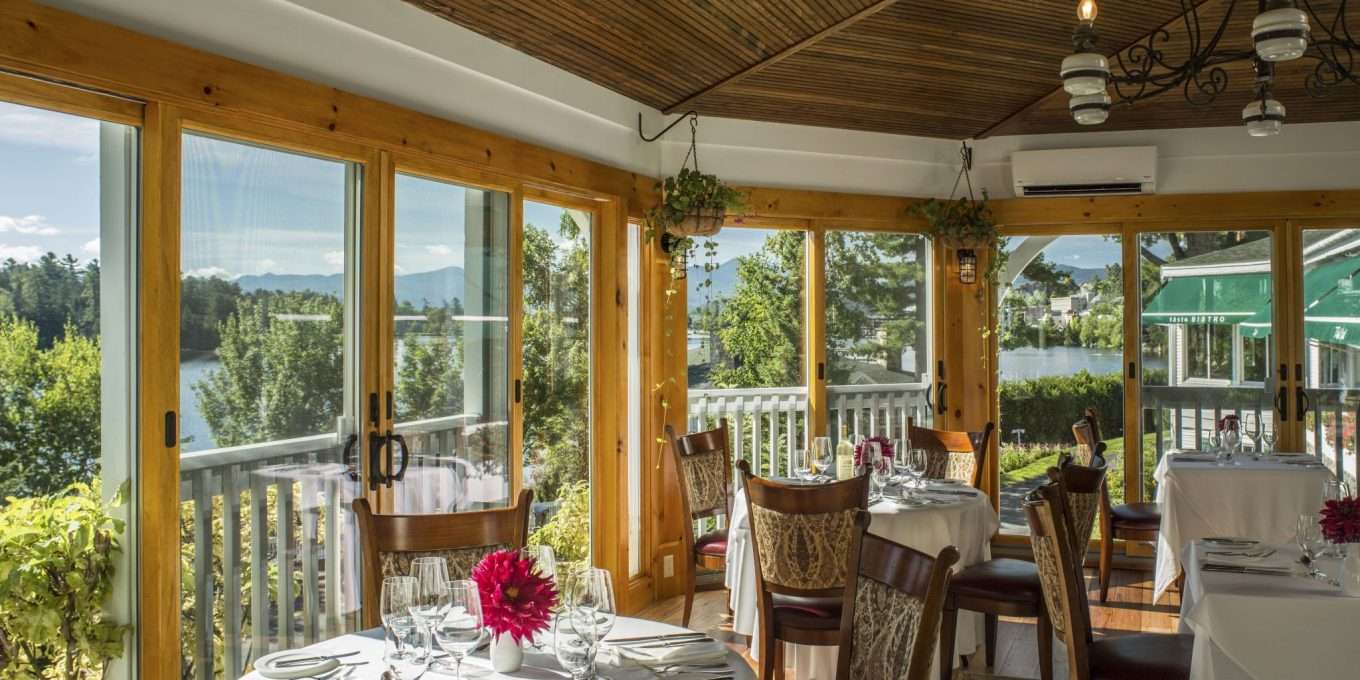 A dining area surrounded by windows overlooking a lake