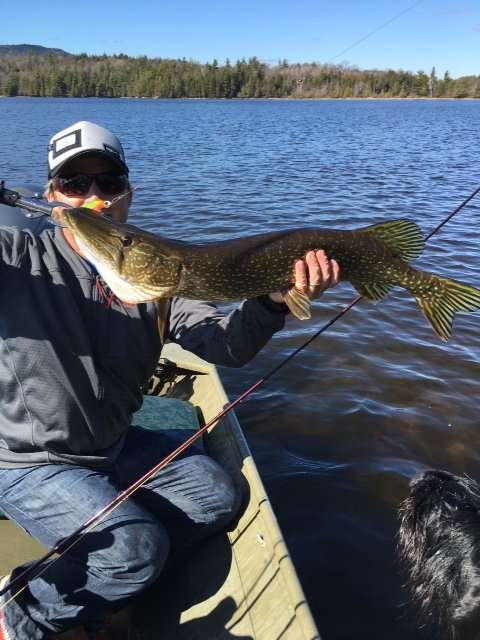 Andrew Weibrecht holding a large fish while sitting on a boat on the lake