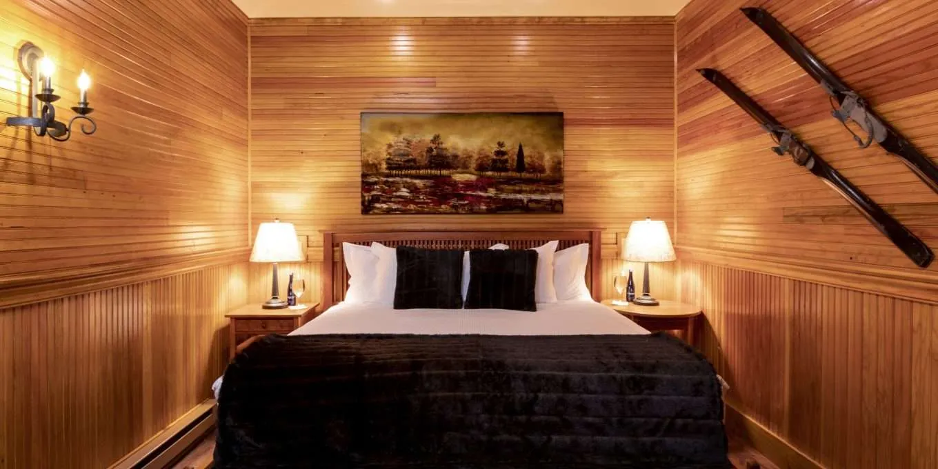 A large bed centered in a room with matching side tables and wooden walls