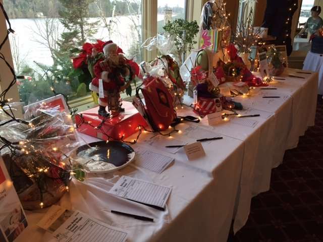 Christmas themed auction items on table with lights against a window