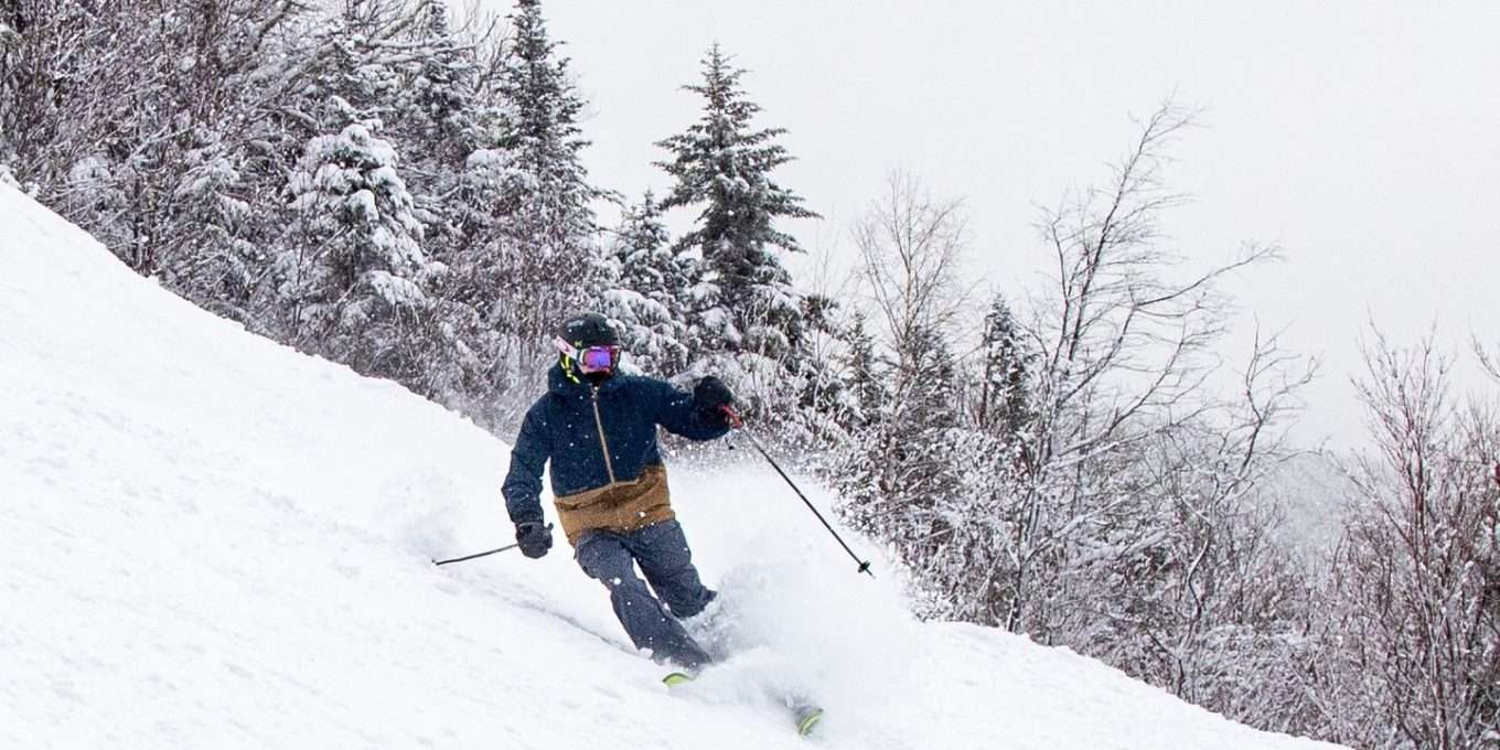A skier kicks up snow on a downhill slope