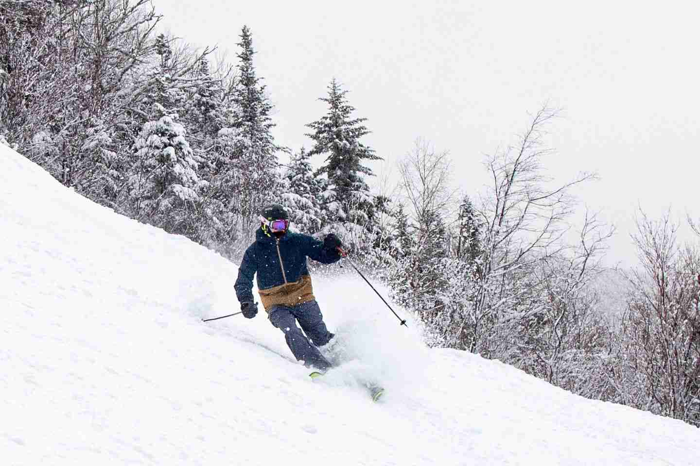 A skier kicks up snow on a downhill slope