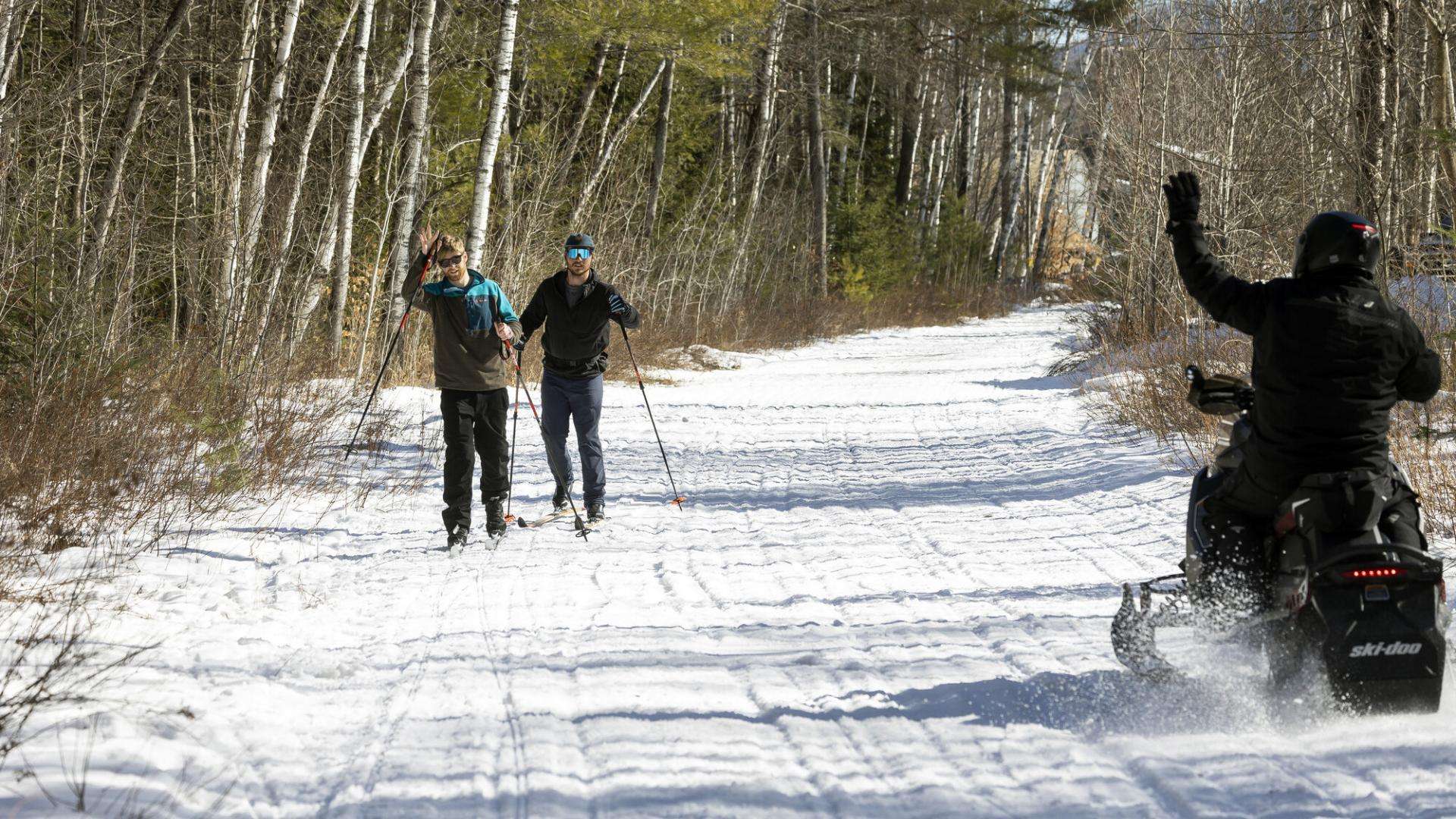 Snowmobile rider and cross country skiers on trail